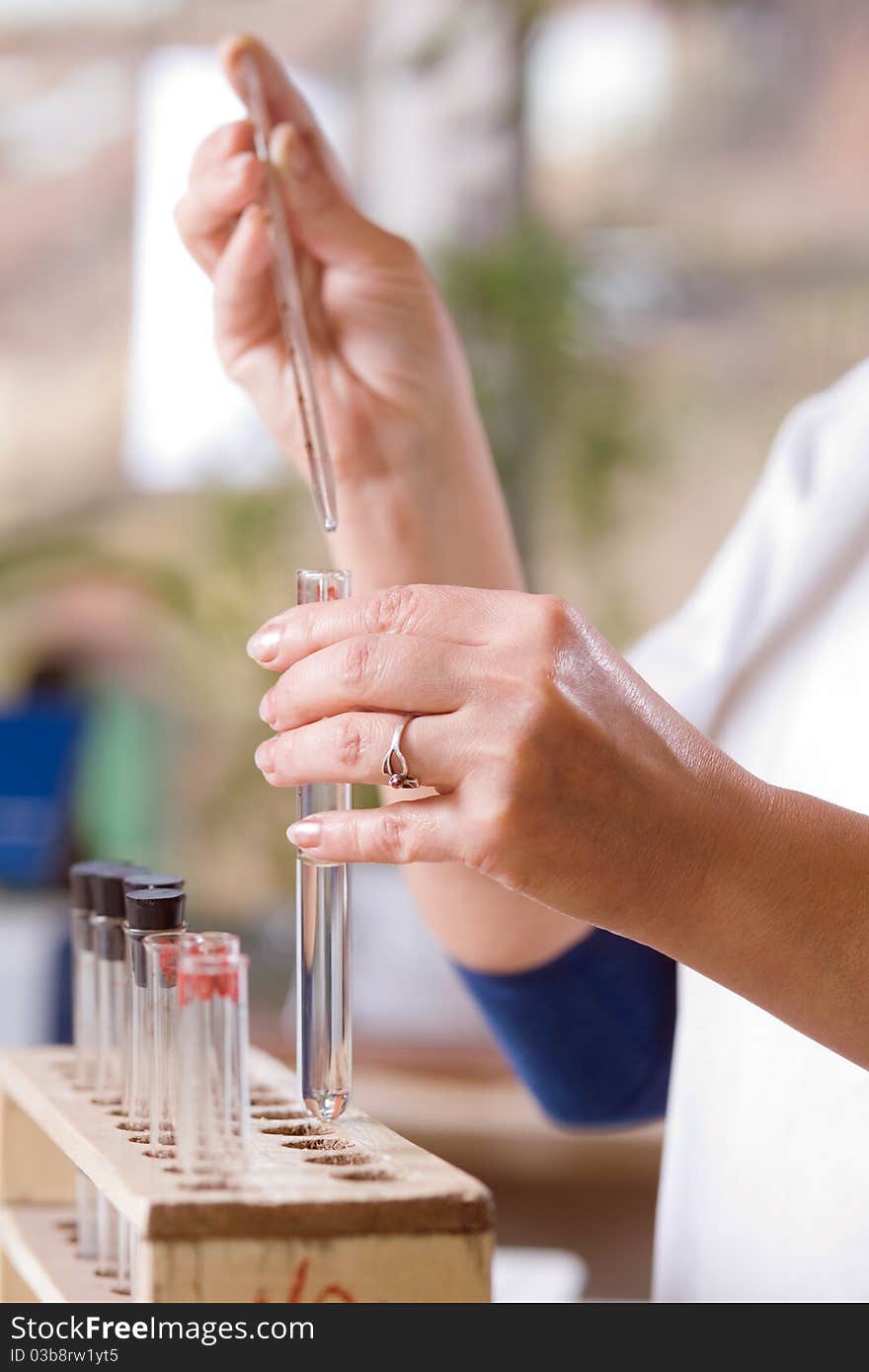 Woman pours a drop of liquid in a flask