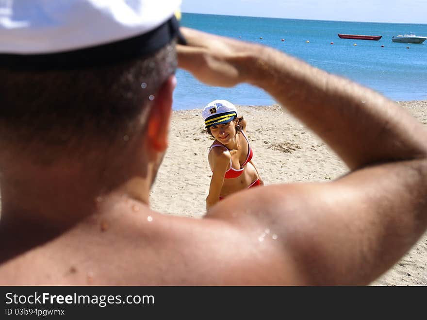 Beautiful young woman in a red swimsuit plays with a young sailor's desires and temps him to come to the sea. Beautiful young woman in a red swimsuit plays with a young sailor's desires and temps him to come to the sea.