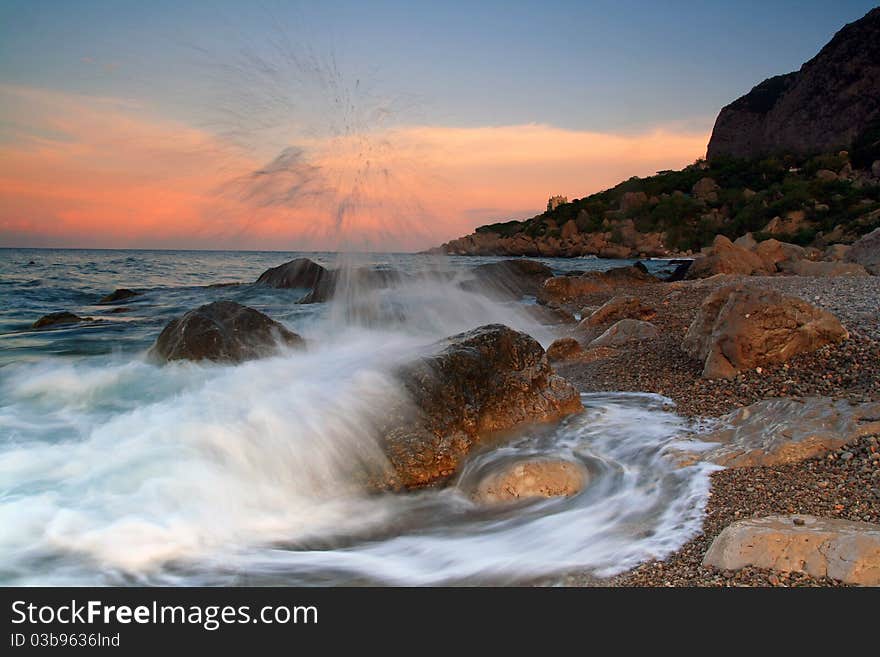 Waves crash on a rock in the dawn on the ocean coast. Waves crash on a rock in the dawn on the ocean coast