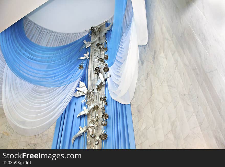 From the ceiling of the hall a solemn marriage down the white and blue curtains decorating the room. From the ceiling of the hall a solemn marriage down the white and blue curtains decorating the room