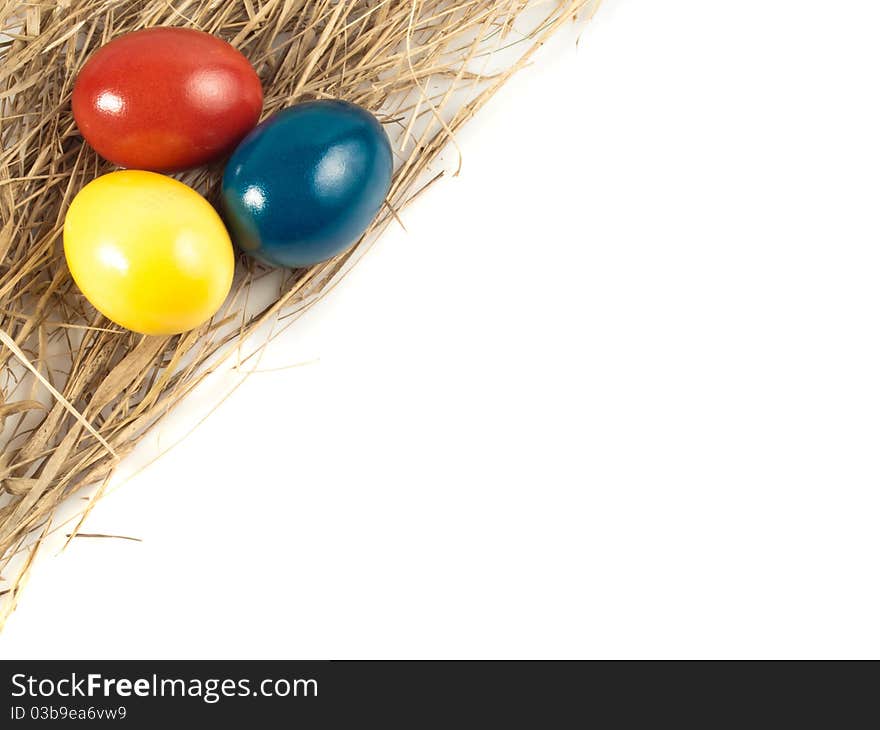 Three Easter eggs lying on straw, isolated with white background