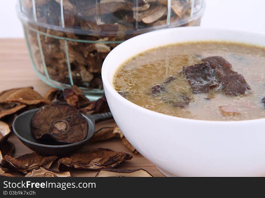 Mushroom soup in a bowl with dried mushrooms surrounding it and some in a jar, and an antique spoon. Mushroom soup in a bowl with dried mushrooms surrounding it and some in a jar, and an antique spoon