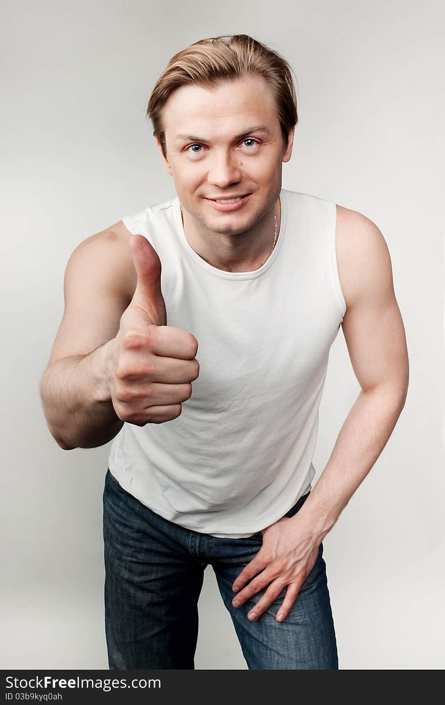 Young man with thump up on the gray background. Young man with thump up on the gray background