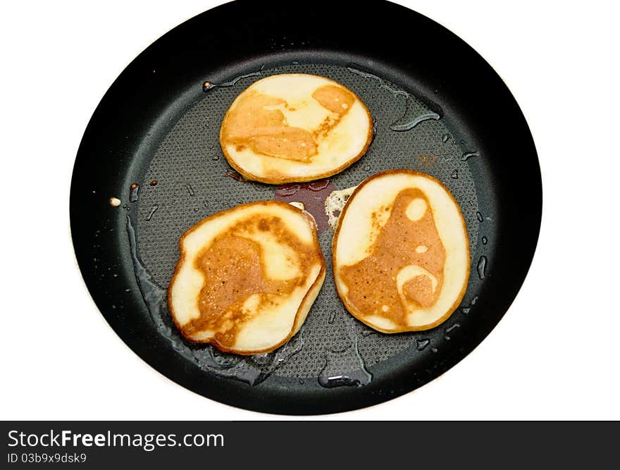 Fritters on a frying pan pancakes on the griddle on the white isolated background