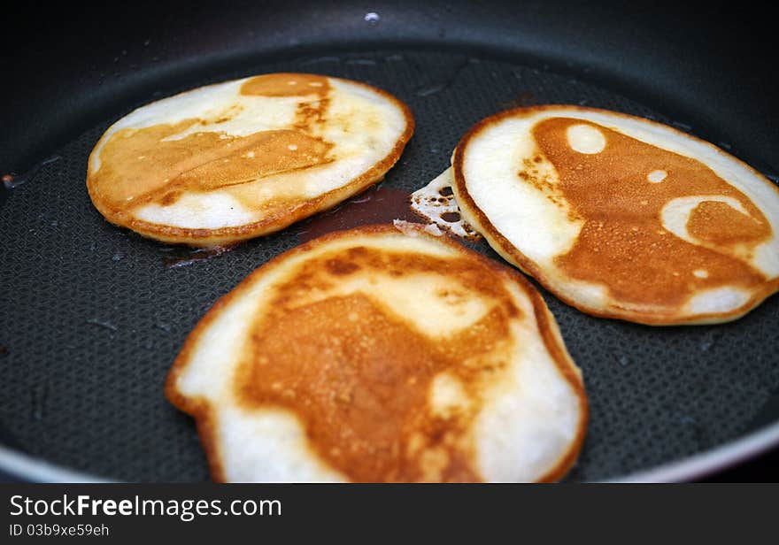 Fritters on a frying pan pancakes on the griddle on the white isolated background