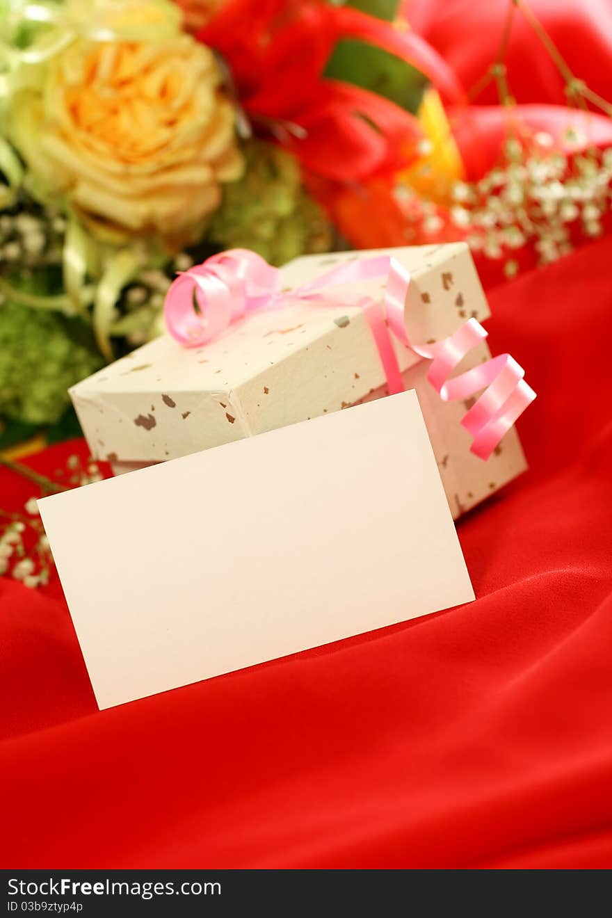 Blank card, gift and flowers on red background