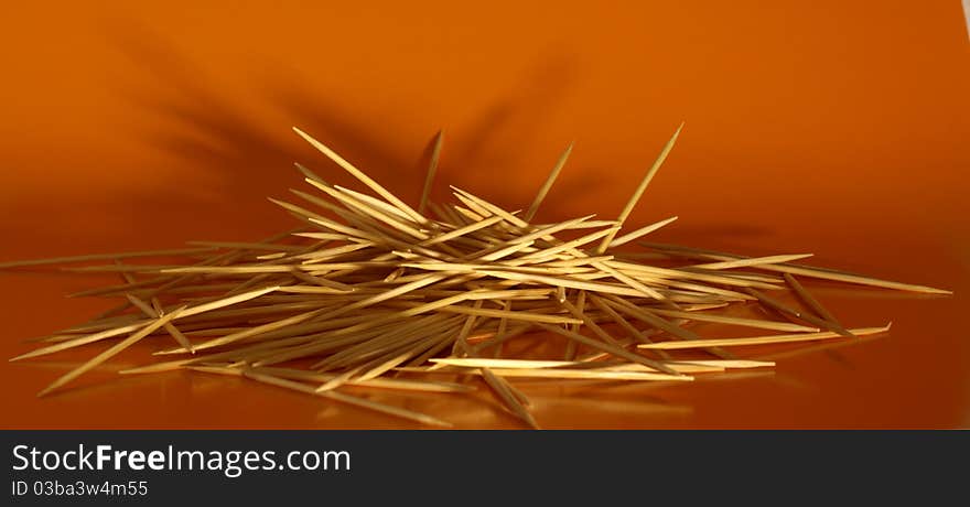 Pile of wooden toothpicks on yellow background. Pile of wooden toothpicks on yellow background