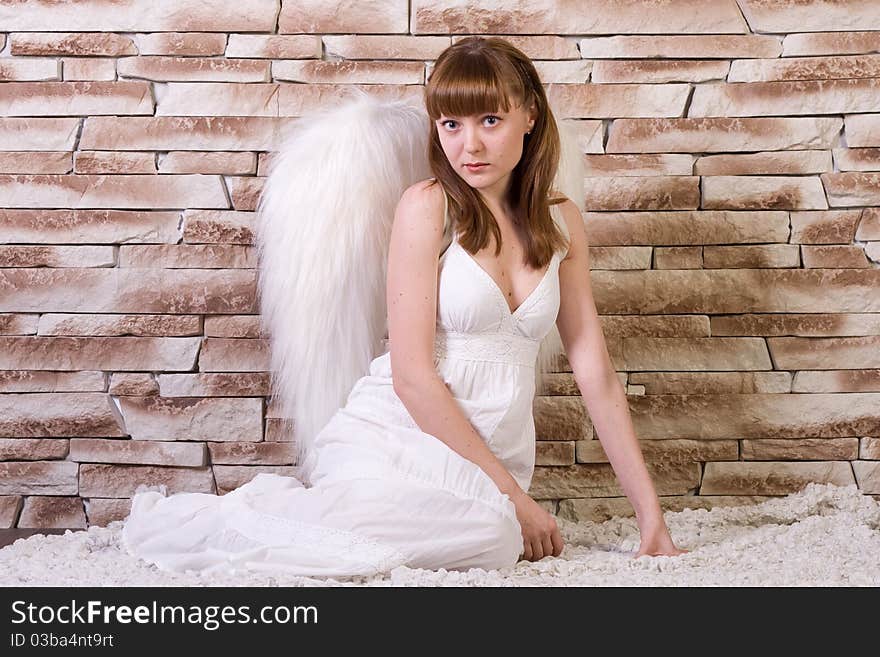 Angel girl on brick wall background. Siting poses