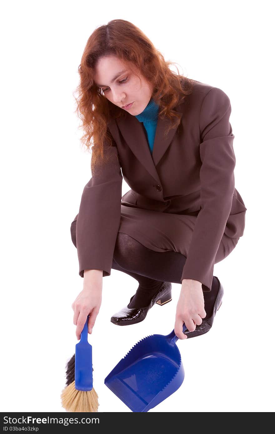 A young woman is sweeping up dirt with a hand brush. A young woman is sweeping up dirt with a hand brush