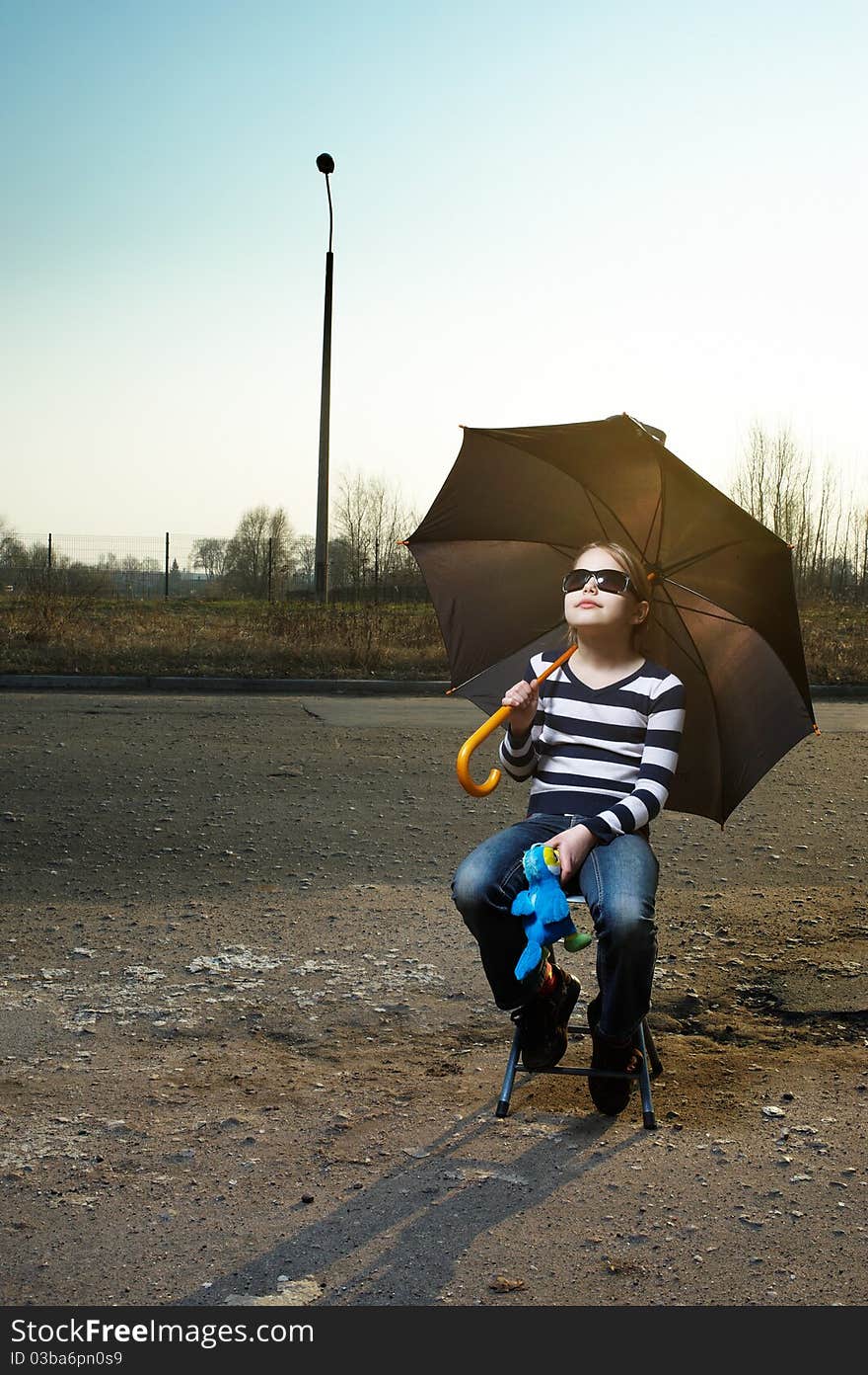 Little girl in sunglasses and with umbrella sitting. Outdoor portrait. Little girl in sunglasses and with umbrella sitting. Outdoor portrait