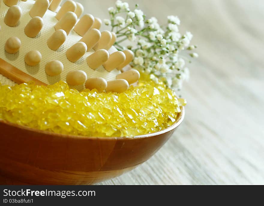 Yellow bath salt in bowl and flowers