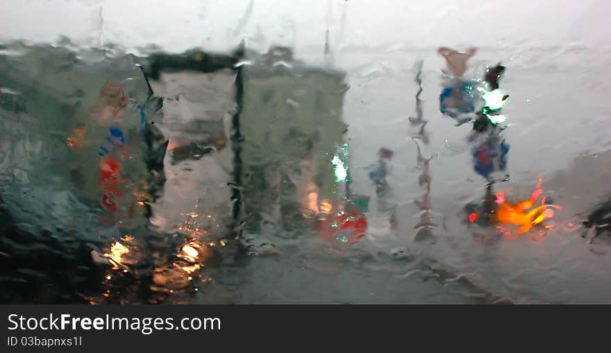 View of the city street at dusk in the rain through the glass. View of the city street at dusk in the rain through the glass