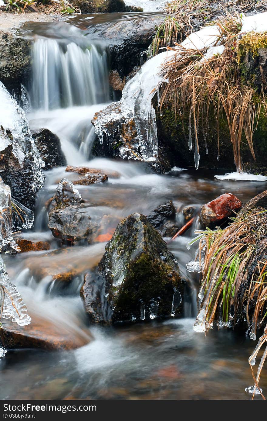 An icy stream running through rocks and grass