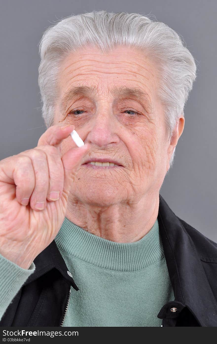 Senior woman holding a tablet or pill in one hand