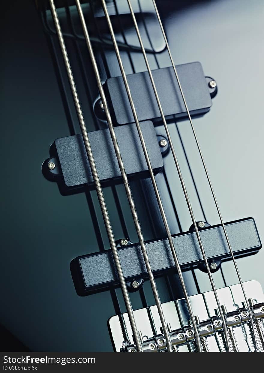 Closeup of black five cords electric bass and pickups. Vertical shape, studio shot. Closeup of black five cords electric bass and pickups. Vertical shape, studio shot