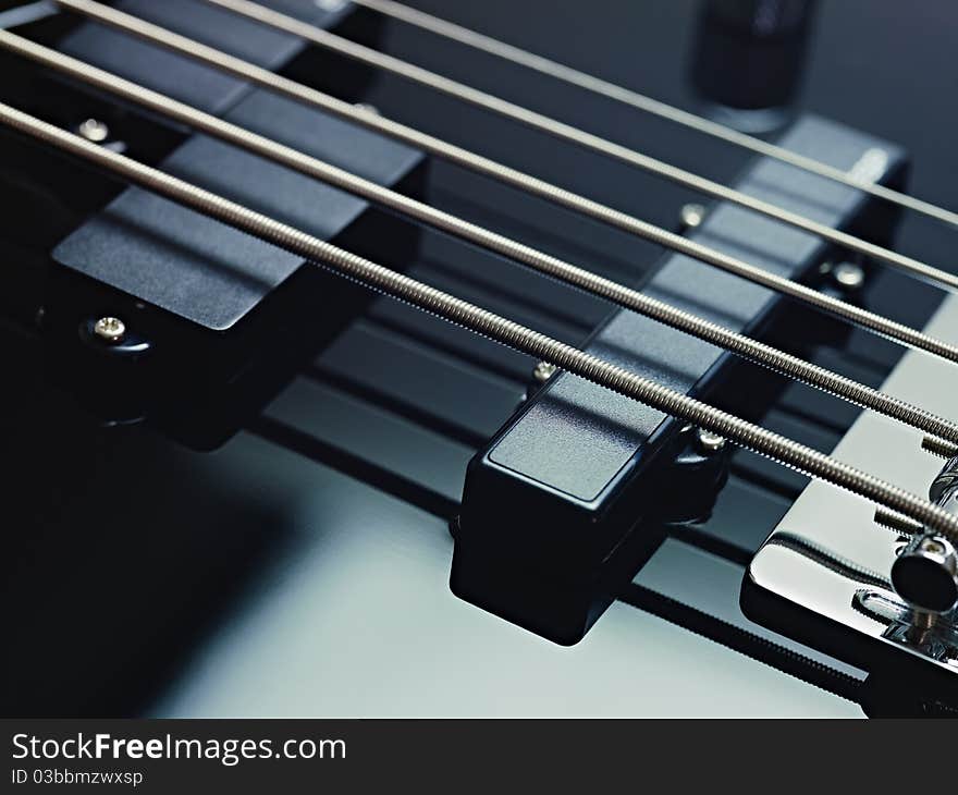 Closeup of black five cords electric bass and pickups. Horizontal shape, studio shot. Closeup of black five cords electric bass and pickups. Horizontal shape, studio shot