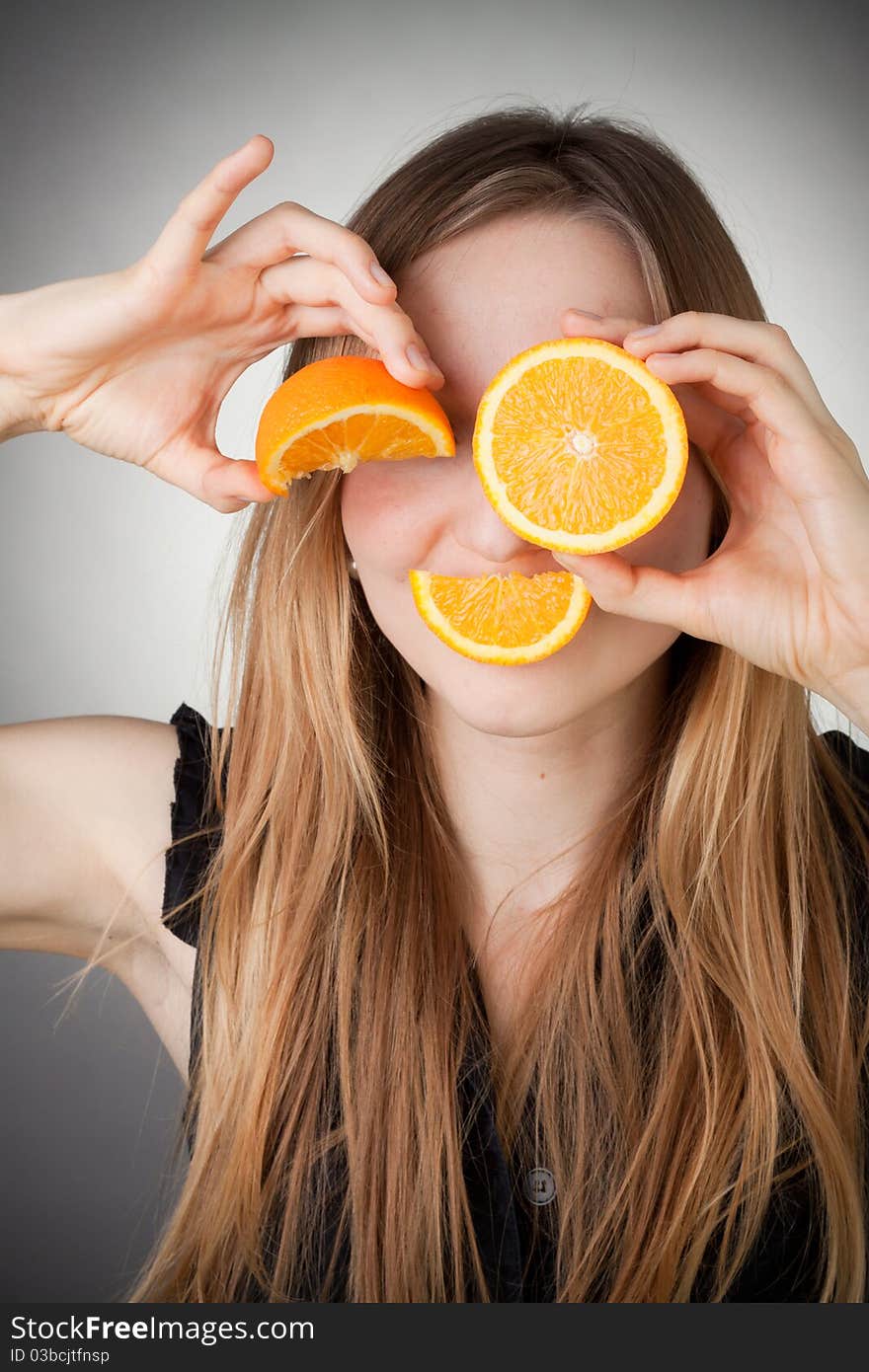 Girl using orange as eyes, with grey background