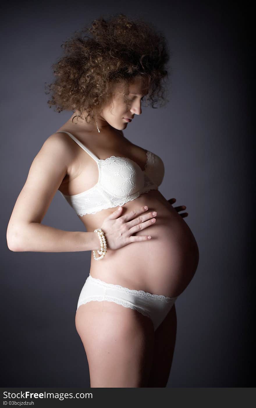 Studio art photography of a pregnant woman on gray background