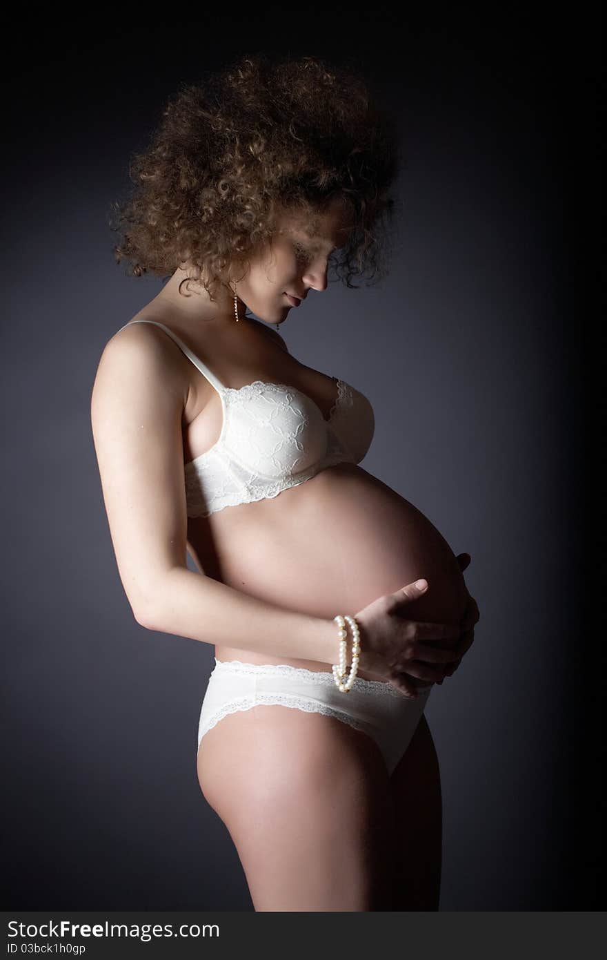 Studio art photography of a pregnant woman on gray background