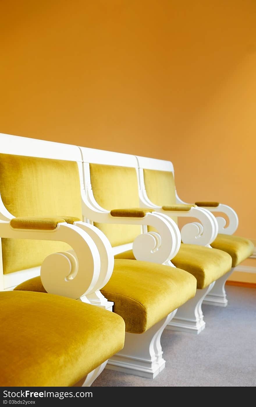 Row of yellow armchairs against a wall. Row of yellow armchairs against a wall.