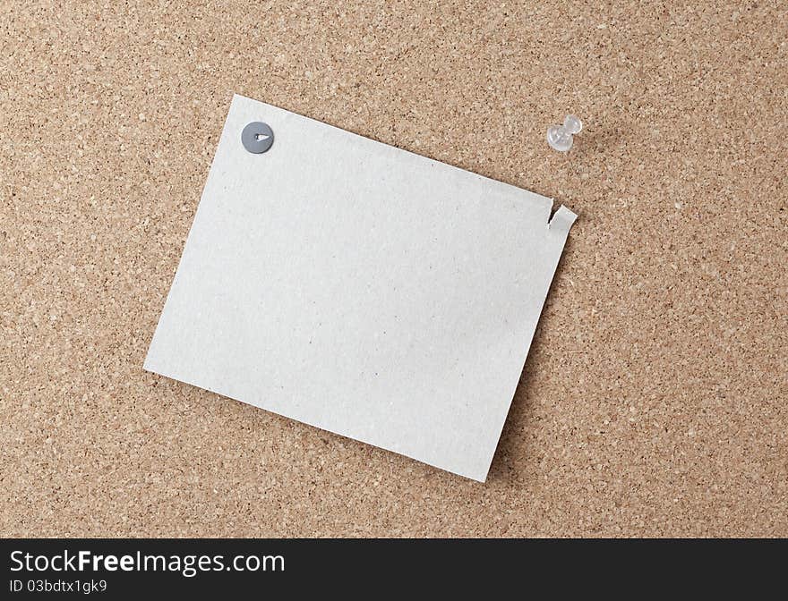 Sheet of paper attached to a pushpin noticeboard. One side of the leaf torn.