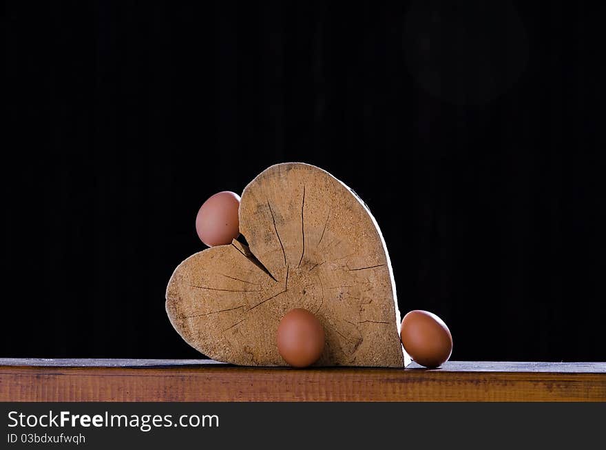 Still life of a wooden heart in the sun and some natural eggs around it. Still life of a wooden heart in the sun and some natural eggs around it.