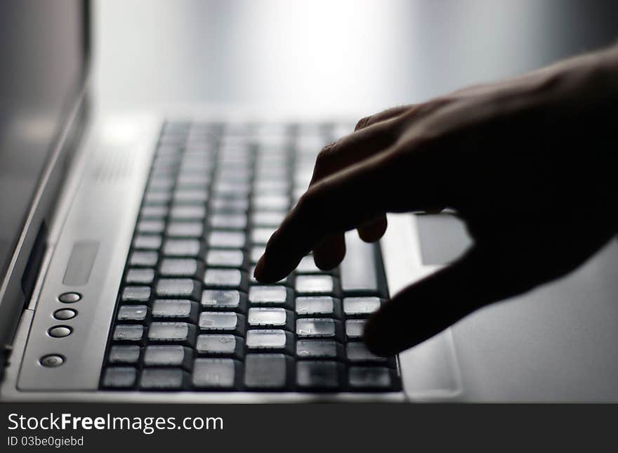 Hand on gray laptop keyboard. Hand on gray laptop keyboard