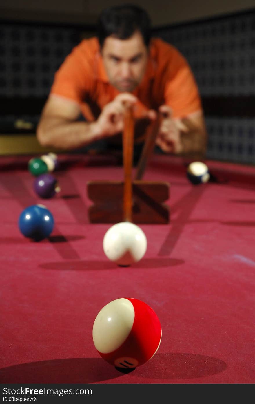 Snooker player taking a long shot across the table (focus on the first ball). Snooker player taking a long shot across the table (focus on the first ball)