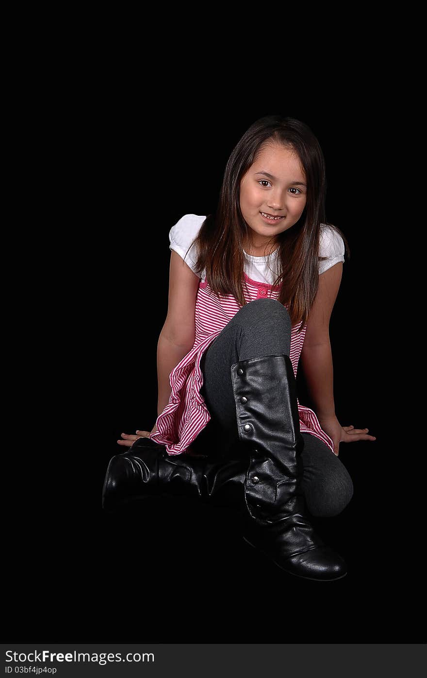 A young girl in tights and a pink dress and boots holding sitting on the floor in the studio, for black background. A young girl in tights and a pink dress and boots holding sitting on the floor in the studio, for black background.