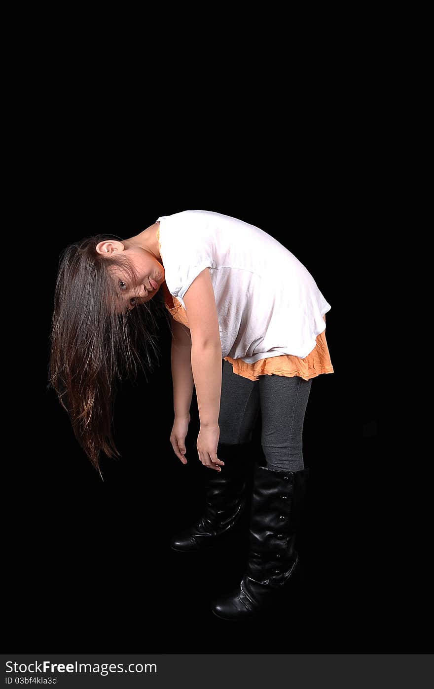 A young girl in tights and a pink dress and boots holding her head down her long hair falls down, for black background. A young girl in tights and a pink dress and boots holding her head down her long hair falls down, for black background.