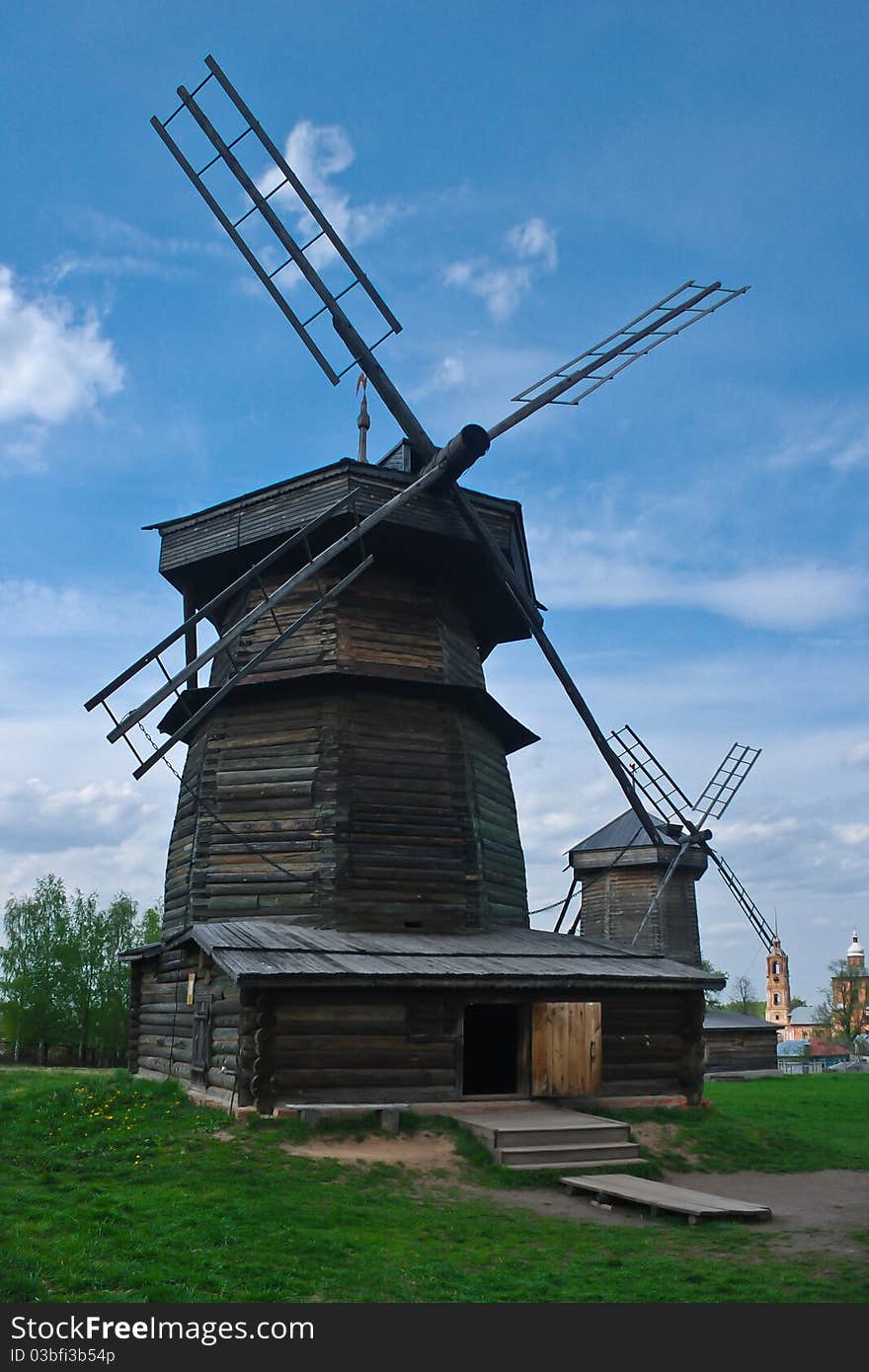 Wooden windmills in warm weather. Green summer lawn. Clear sky. Wooden windmills in warm weather. Green summer lawn. Clear sky.