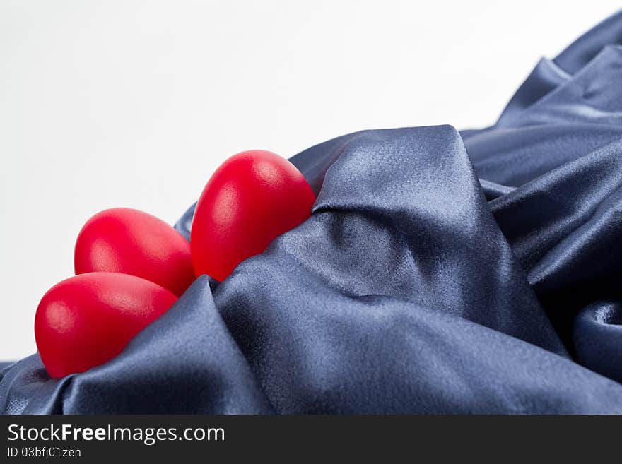 Red Easter eggs on a blue satin textile.