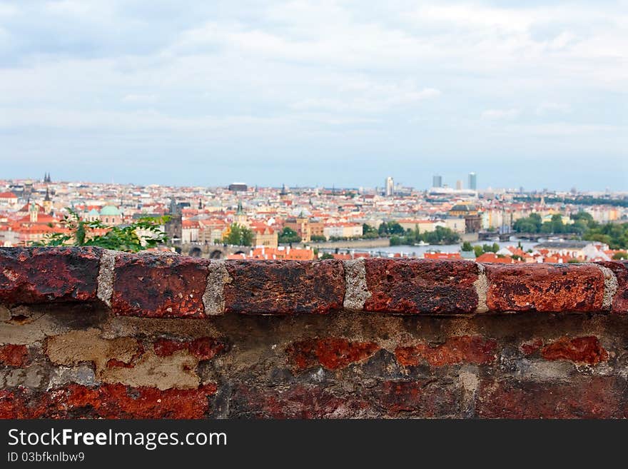 Fragment of old brick wall with old city and sky on background. Fragment of old brick wall with old city and sky on background