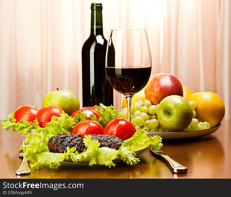 Grilled cutlets with tomatoes, red wine and grapes served on a wooden table. Grilled cutlets with tomatoes, red wine and grapes served on a wooden table