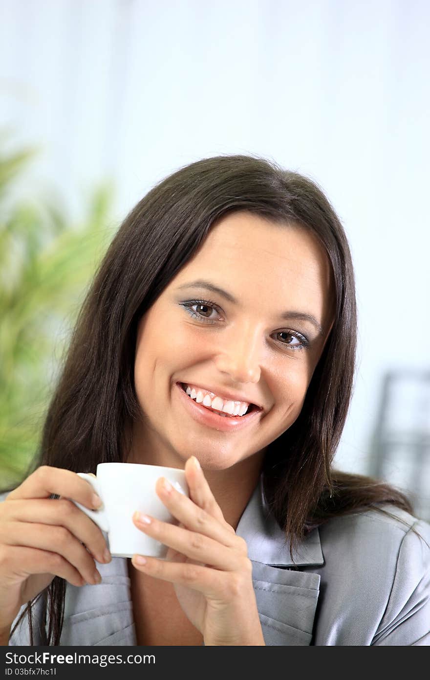 Portrait of a smart young businesswoman reading paper and drinking coffee at office