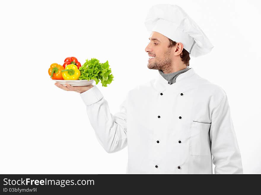 Happy cook holding a plate with vegetables on white background. Happy cook holding a plate with vegetables on white background