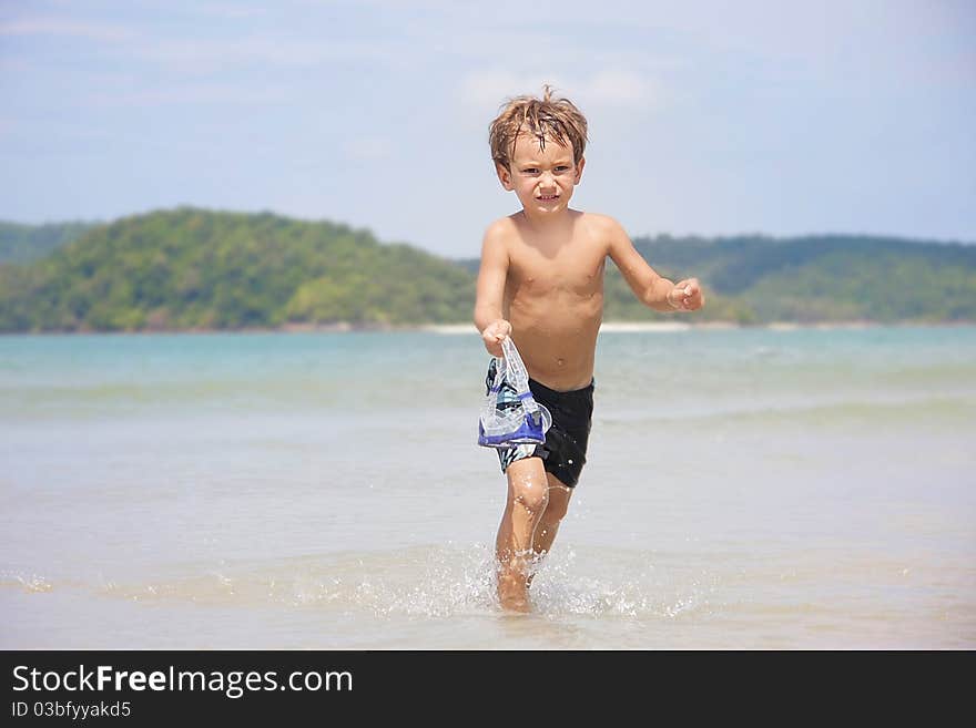 Young boy running with mask on beach. Young boy running with mask on beach