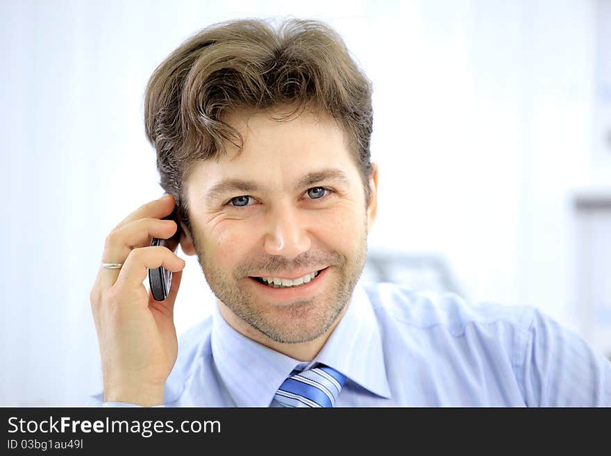 Handsome business guy working on cellphone and laptop together while at work