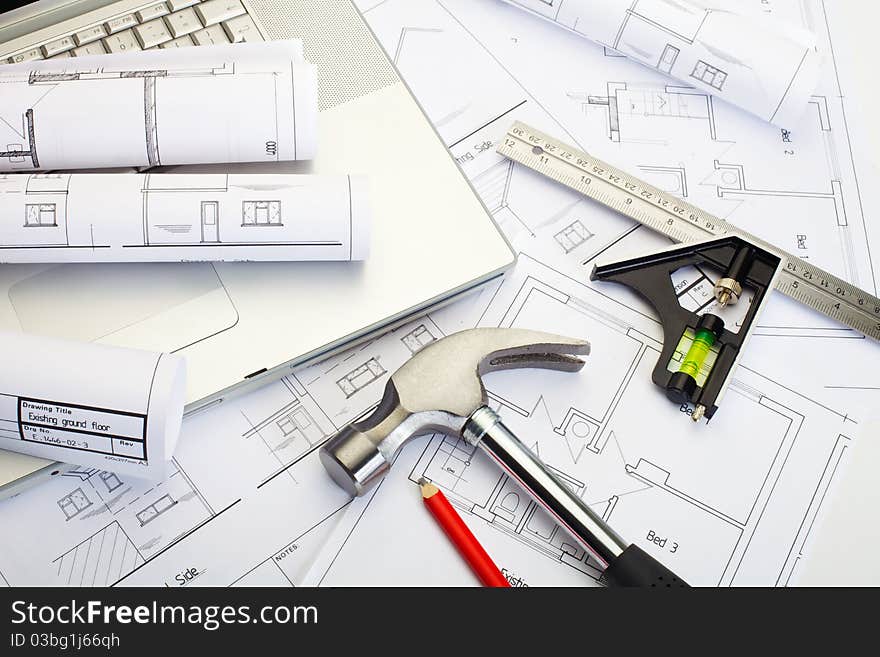 Close up of builder's plans with a laptop and tools. Close up of builder's plans with a laptop and tools