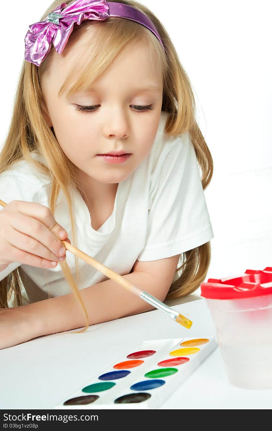 Cute little girl with a brush and paints