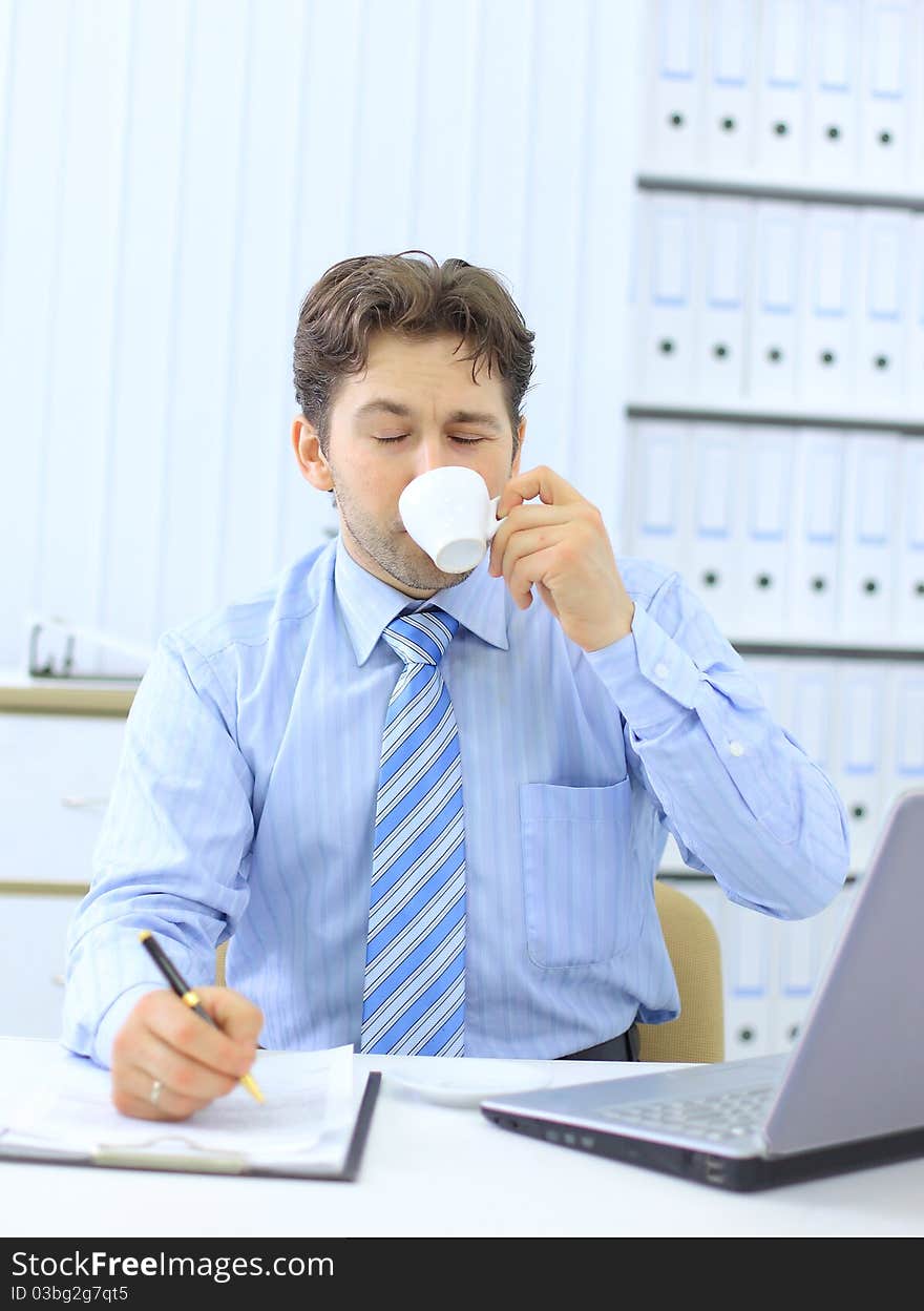 Portrait of a young business executive drinking coffee while looking at the computer