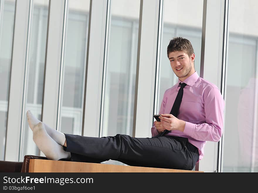 Young business man talk by cellphone over bright window in big hall