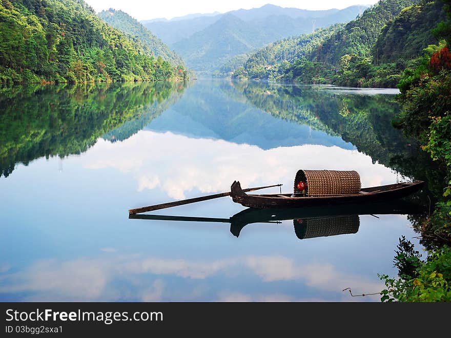 Boat in the river with clear reflection and blue sky.