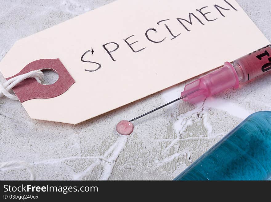 Syringe with pink liquid next to a tag which says Specimen.