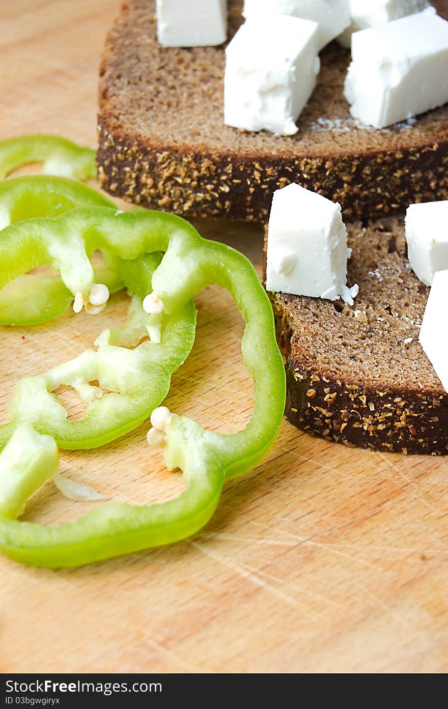 Feta cheese cubes with bread and pepper on wooden board