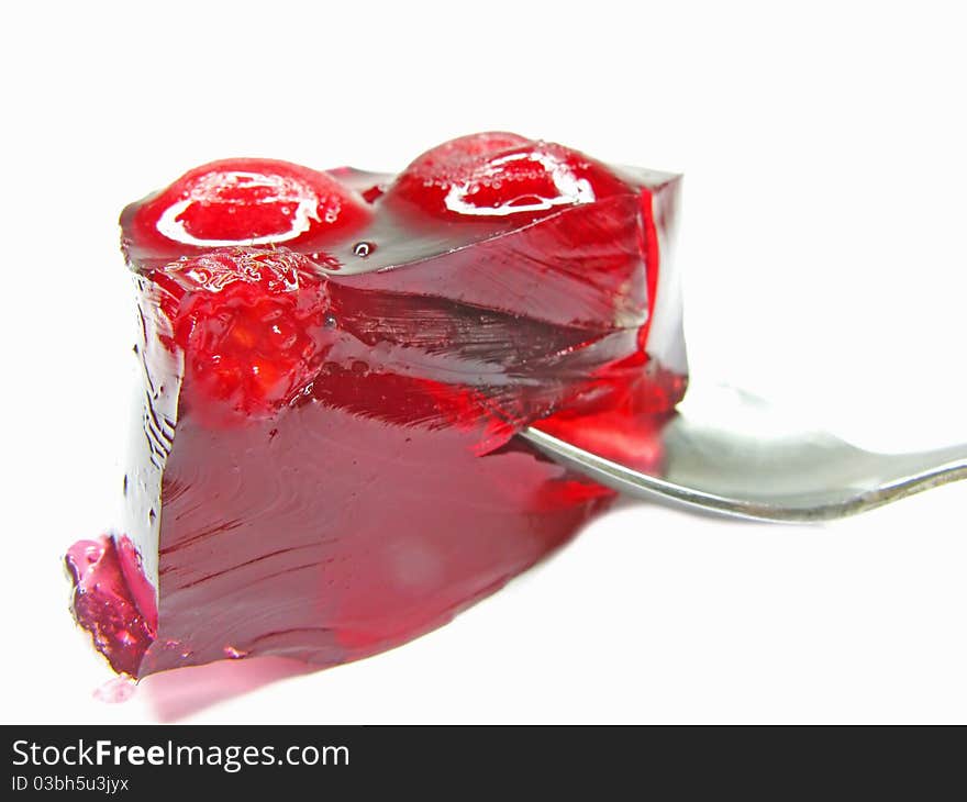 Red marmalade dessert with cherry with spoon inside isolated. Red marmalade dessert with cherry with spoon inside isolated