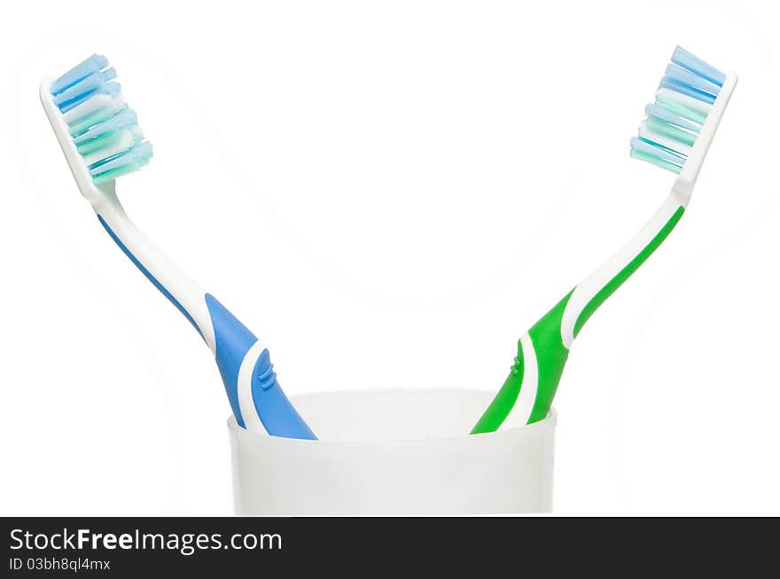 Two toothbrushes in glass. Focus is pointed at the bristle brushes