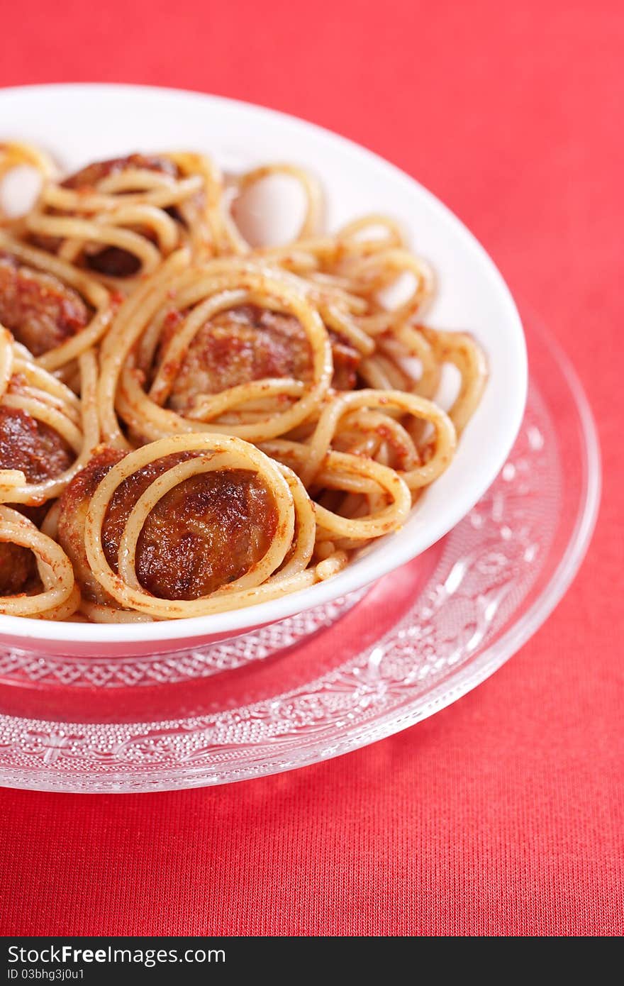 Pasta with meatballs and tomato sauce on red background