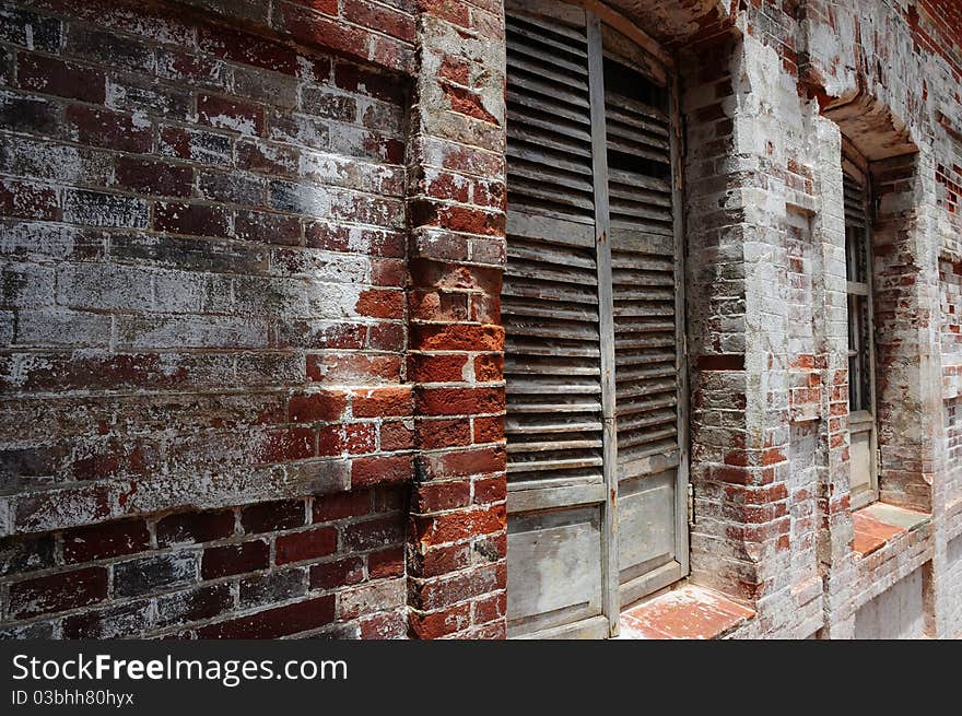 Old brick wall with red bricks and broken wooden windows.