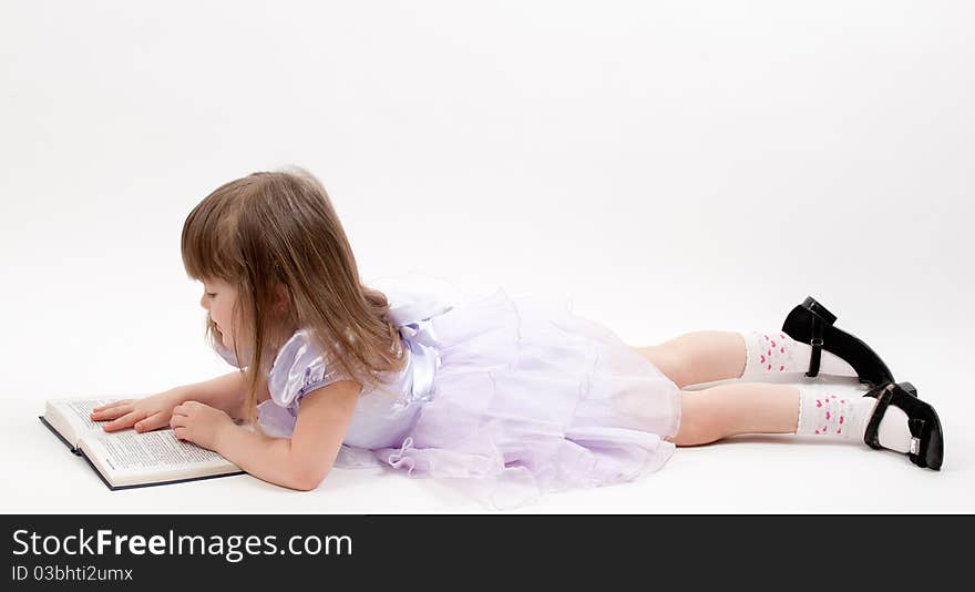 Young girl in pink dress lying and reading a book. Young girl in pink dress lying and reading a book